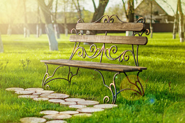 Wooden bench with iron forging pattern in a park on sunny day.