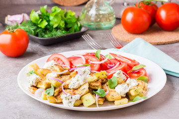 Fried zucchini with feta cheese, tomatoes, herbs and onions on a plate. Delicious appetizer ready to eat