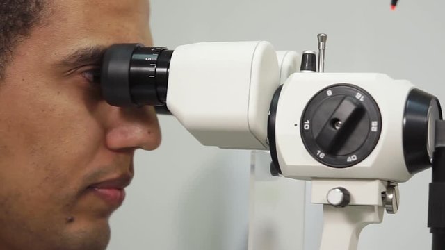 Close up shot of male oculist examining eyes using slit lamp biomicroscopy. Problems with eyes.