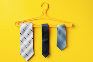 three men's ties are hanging on hanger, yellow background