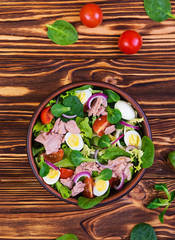 Salad with tuna, tomatoes, quail eggs, asparagus and onions on wooden background