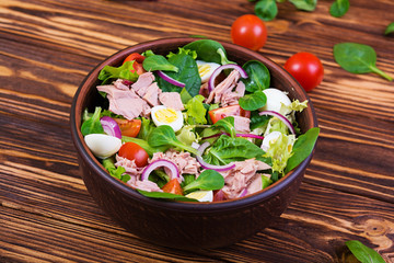 Salad with tuna, tomatoes, quail eggs, asparagus and onions on wooden background