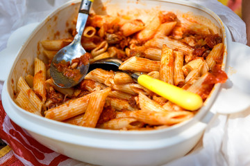 Eating macaroni pasta from plastic container bowl in nature camping.