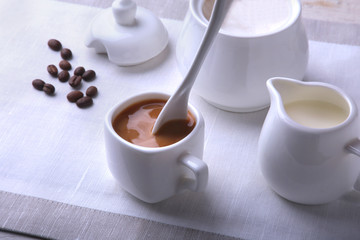 Cup of hot coffee espresso, coffee beans, jug of milk, and bowl with sugar on white background for copy space. Coffee concept.