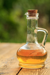 Apple vinegar in glass bottle on wooden boards with green natural background