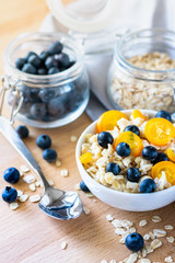 healthy breakfast: oatmeal porridge with blueberries and kumquat, next to a glass jar of blueberries and oatmeal. the concept of diet and healthy lifestyle