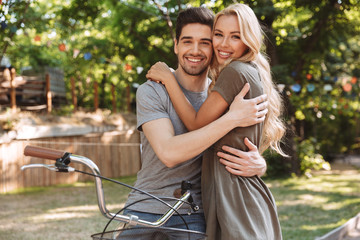 Smiling lovely young couple posing together with bicycle