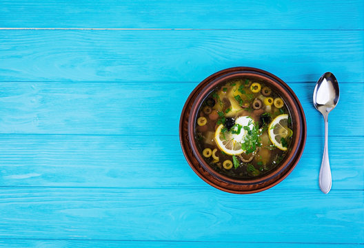 Russian soup solyanka with sour cream on wooden background