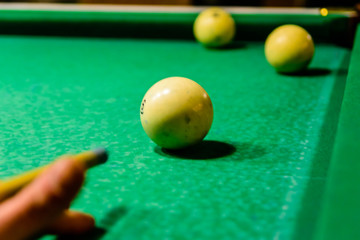 Player arm with the cue and balls on the green cloth. Russian billiard