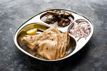 Mini chicken curry Thali with chapati/roti, popular indian lunch/dinner menu. served in a stainless steel oval plate with salad. selective focus