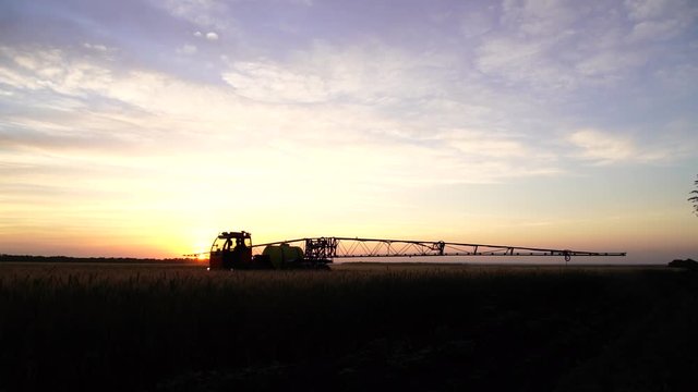 Machine for spraying pesticides and herbicides in the field at work at sunset. Video with part time slow motion effect.
