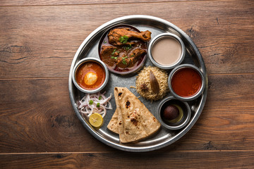 Fototapeta na wymiar Kolhapuri chicken Thali is a popular Indian/asian food platter consists of poultry meat, egg curry with chapati ,rice, salad and sweet Gulab Jamun