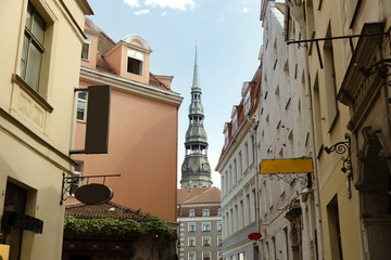 Beautiful small street and church tower in Old Town of Riga, Latvia. City tour, travel