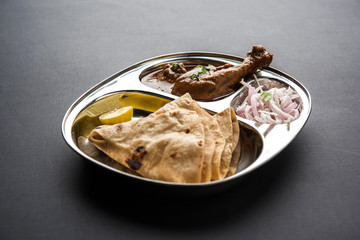 Mini chicken curry Thali with chapati/roti, popular indian lunch/dinner menu. served in a stainless steel oval plate with salad. selective focus