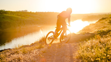 Cyclist Riding the Mountain Bike on the Summer Rocky Trail at the Evening. Extreme Sport and Enduro...