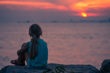 Image of little young girl sitting on the rock