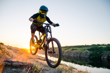 Cyclist Riding the Mountain Bike on the Summer Rocky Trail at the Evening. Extreme Sport and Enduro Cycling Concept.