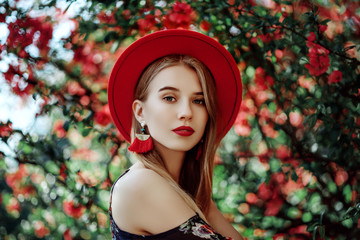 Outdoor portrait of young beautiful girl with red lips, long blonde hair, wearing hat, long tassel...
