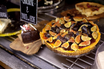 Delicious tart with fresh figs on display showcase. Modern bakery with different kinds of cakes and...