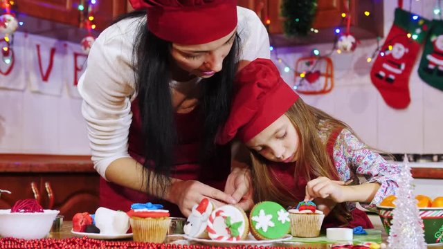 Mother and daughter are decorating with sugar mastic a Christmas cupcake