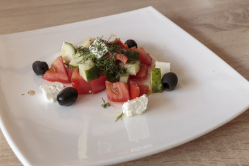 Greek salad with fresh vegetables, feta cheese, tomatoes, herbs and black olives. Cold appetizer,...