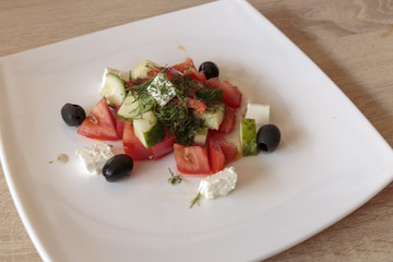 Greek salad with fresh vegetables, feta cheese, tomatoes, herbs and black olives. Cold appetizer, Vegan food and well-balanced meal.