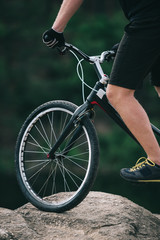 cropped shot of trial biker balancing on rock outdoors