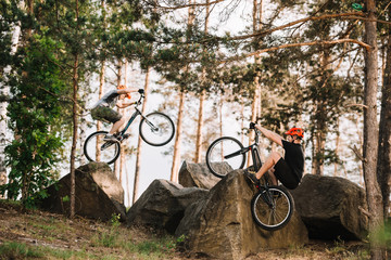 active trial bikers performing stunts on rocks outdoors