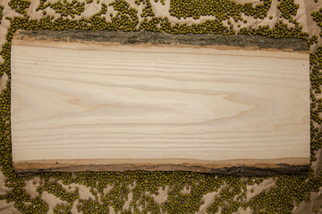 Piece of raw wood with moong dal on crumpled brown paper background. Top view, space for text.