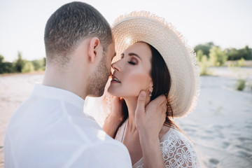 tender man hugging and kissing beautiful woman in hat