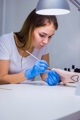Nails painting with brush in nail salon on woman hands