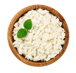 Cottage cheese in a wooden bowl isolated on a white background. Top view. Flat lay
