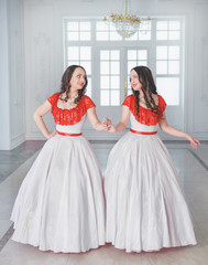 Two Beautiful woman in white and red medieval dresses with crinoline
