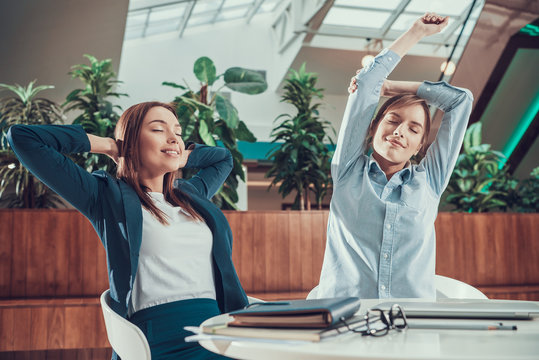Two women exercising stretching in office. - Powered by Adobe