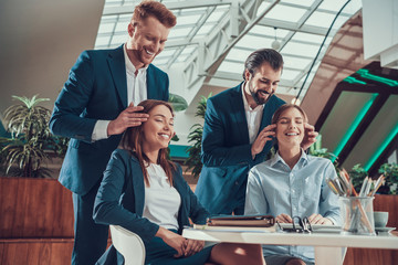 Two men massage heads of two women in office.