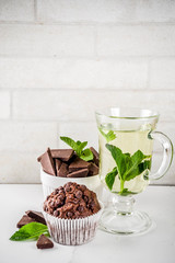 Home baked mint and chocolate muffins with mint tea, white marble background copy space