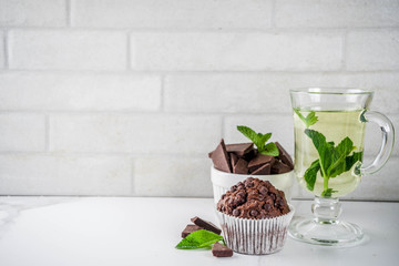 Home baked mint and chocolate muffins with mint tea, white marble background copy space