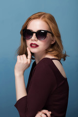 beautiful girl with makeup and red lips in sunglasses on blue background