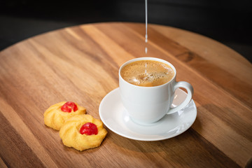 Coffee with pouring milk and cookies.