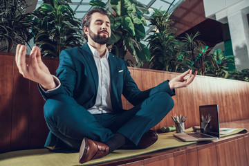 Male worker meditating on bench in office.
