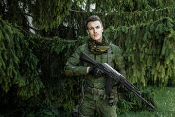 Young male military soldier with a rifle posing outdoors