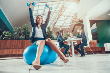 Worker exercising on fitness ball in office.
