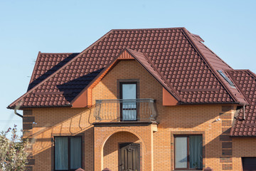 Brick house with balcony, multilevel roof and attic skylights