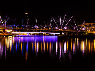 Fototapeta na wymiar purple lights reflecting off water brisbane city story bridge