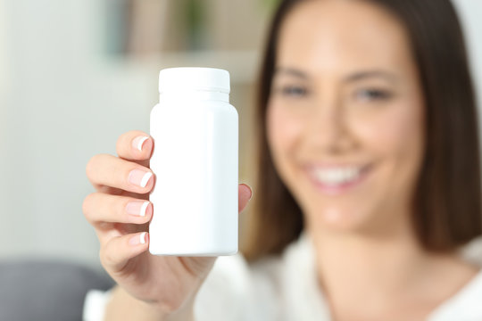 Woman hand showing a blank medicine bottle of pills