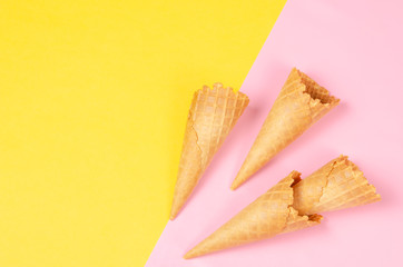 Ice cream waffle cones over bright yellow and sweet pink background with copy space for text, logo or wordings insertion or decoration, summer cold sweet snack