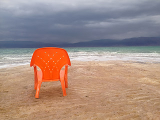 A dramatic colorful view of the empty Dead Sea beach under a deep blue cloudy sky, with lonely...