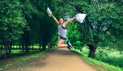 Happy girl jumping with trash bags after doing plogging
