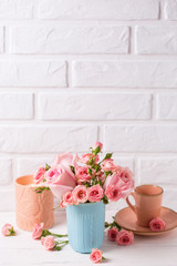 Pink roses flowers in blue cup, burning candle and little cup