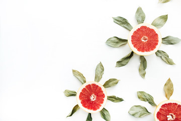 Sun symbol pattern made of sliced grapefruit and leaves. Flat lay, top view summer creative concept.